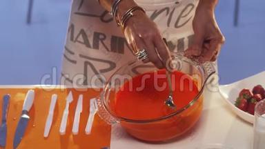 女人`她的手在桌上的大<strong>玻璃</strong>锅里用勺子搅拌橘子粥
